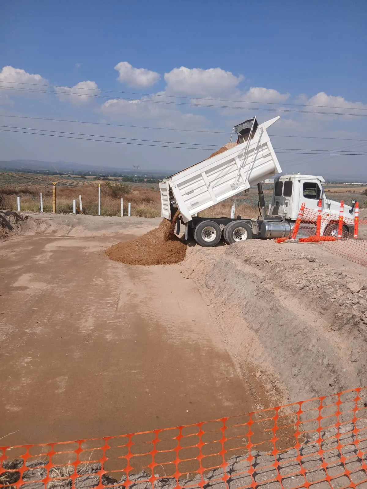 Camión de volteo descargando material en obra