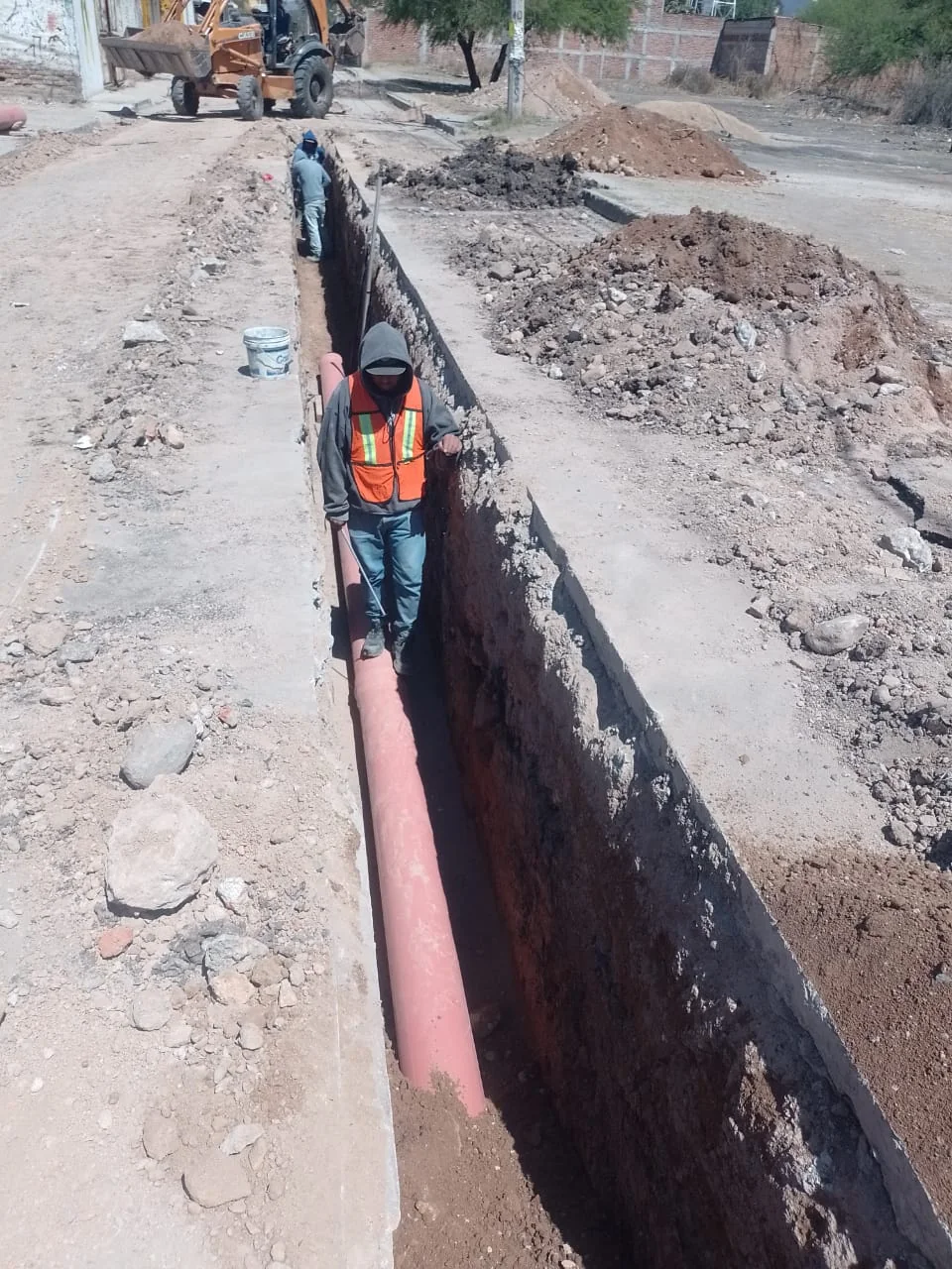 Personal instalando tubería dentro de zanja profunda